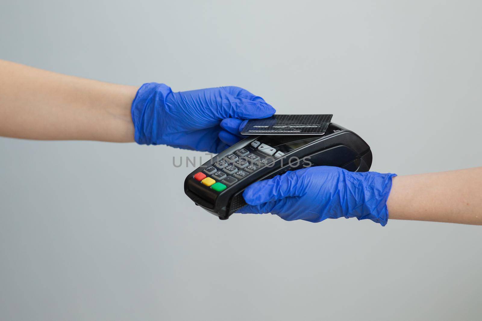 Banking services of electronic money. Financial success and safety. Credit card machine for money transaction. Woman hand in gloves with credit card swipe through pos terminal and enter pin code. by uflypro