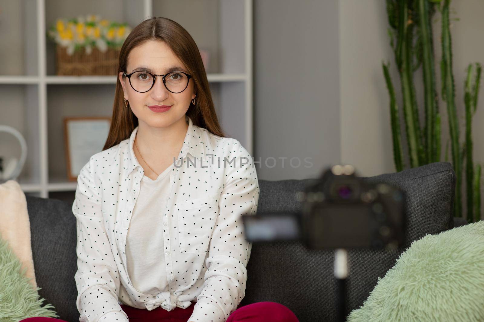 Happy girl at home talking in front of camera. People and technology, young woman at work as vlogger. Web influencer recording message for internet social networks