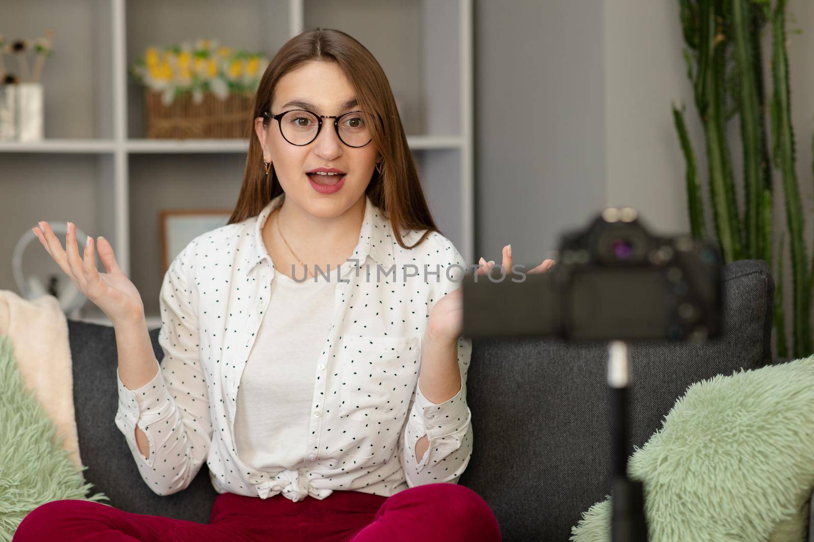 Happy girl at home talking in front of camera. People and technology, young woman at work as vlogger. Web influencer recording message for internet social networks by uflypro