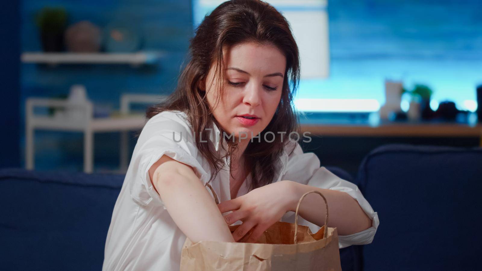 Close up of hungry person unpacking fast food meal from delivery bag on table in living room. Caucasian woman preparing takeaway food and boxes for eating dinner at home after work