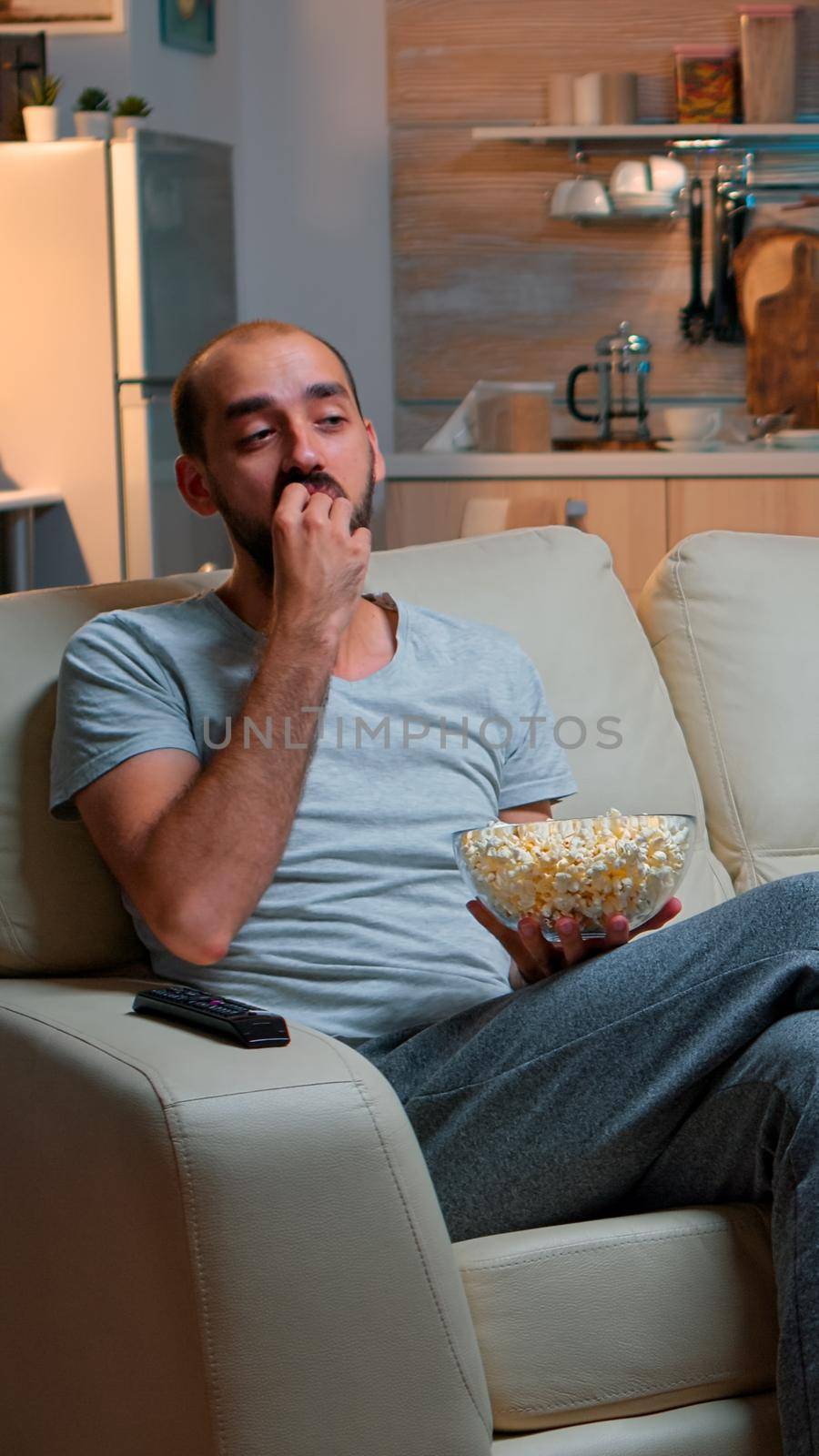 Man eating popcorn and watching TV by DCStudio