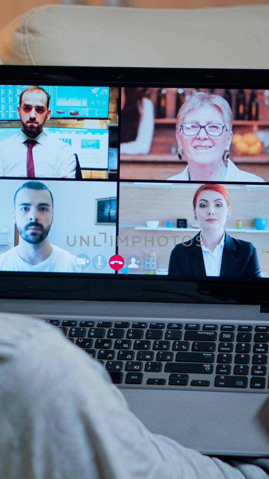 Focused adult using laptop computer during videocall conference talking about social business connection while sitting on couch. Relaxed man working at online communication project overtime in kitchen