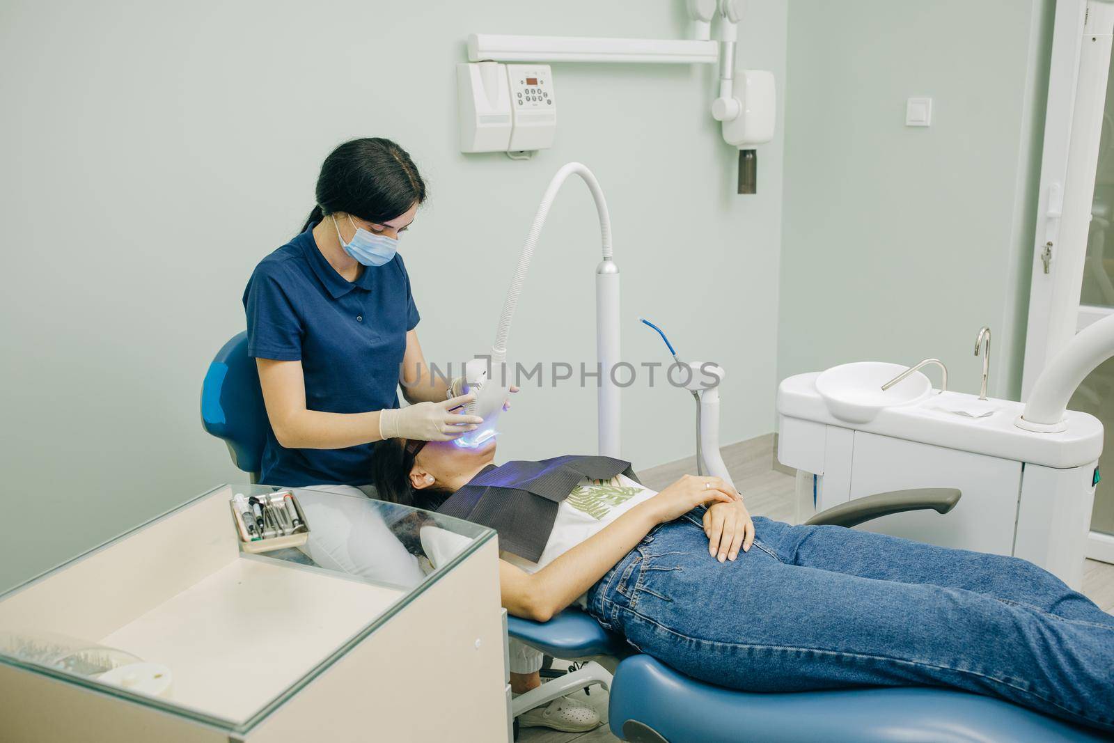 Dentist stomatologist whitening teeth for patient in medicine dental clinic with lamp. Concept of teeth care and dentistry. Teeth whitening procedure.