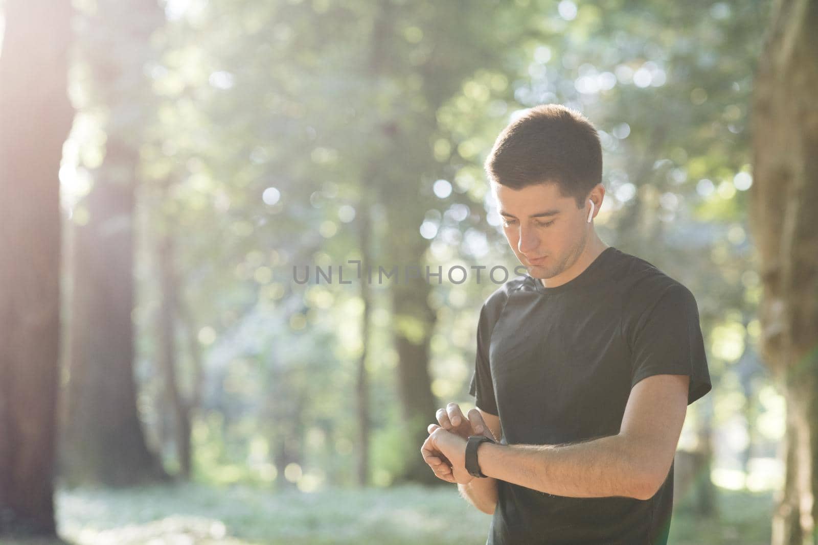 Man runner using smart watch. Handsome guy tracking result after workout. Portrait of fitness man checking result. Sport man looking smart watch by uflypro