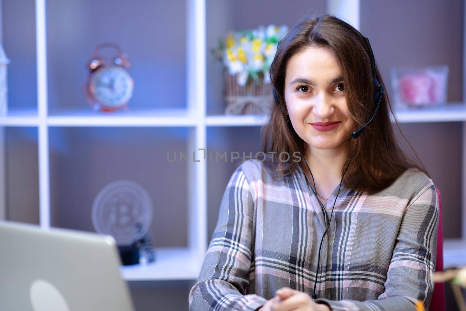 Young woman working from home with laptop and headset.