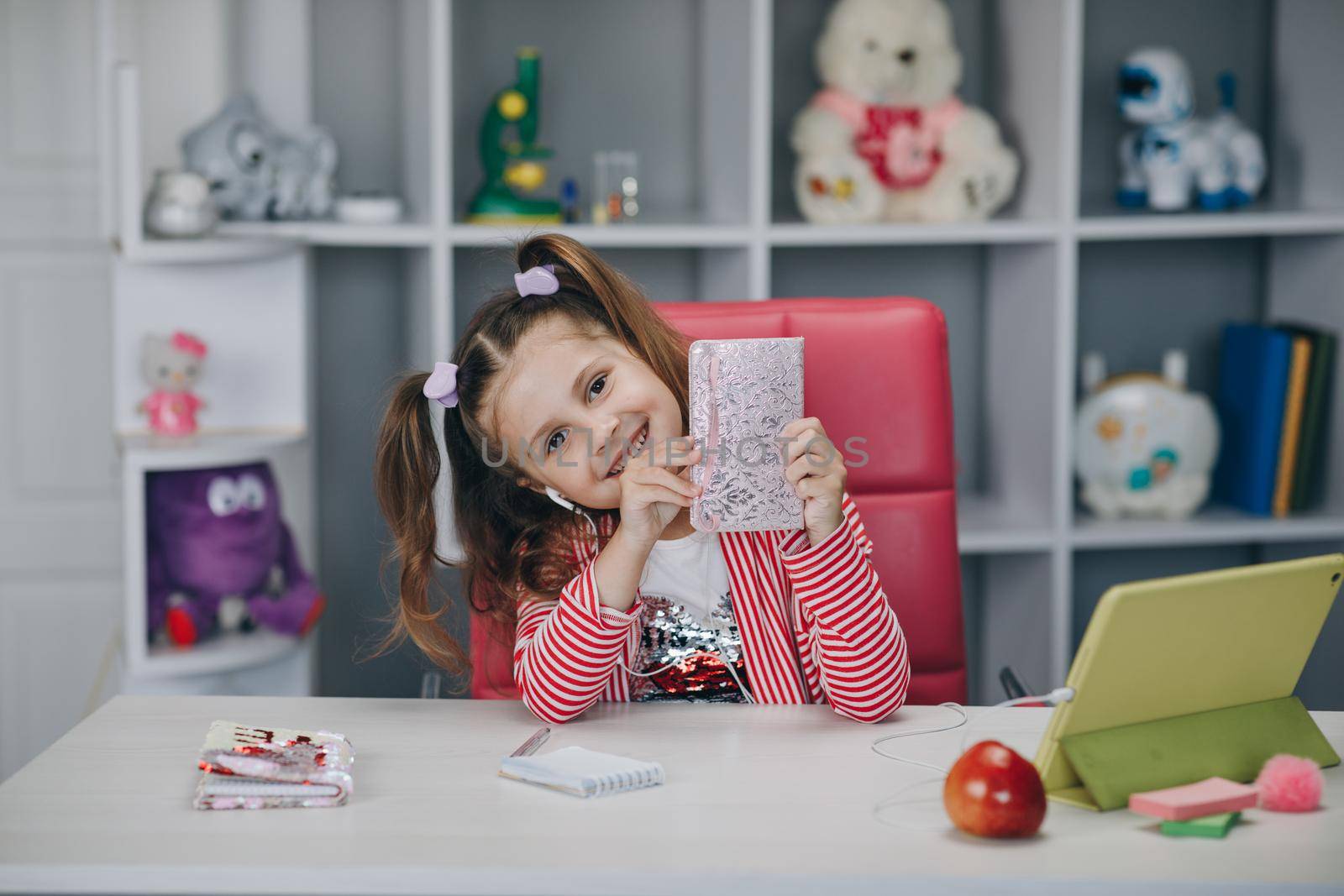 Self isolation and online schooling. Distance learning, school online. Portrait of a preschool girl looking at the book and smiling by uflypro