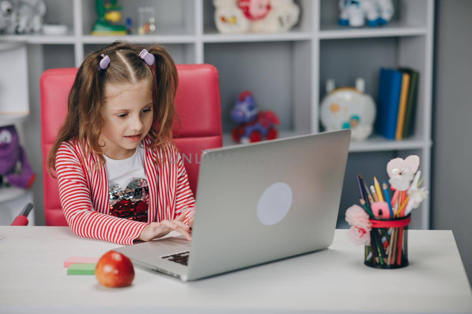 Kid girl calling on laptop distance learning at home. Teen girl chatting by web cam preparing for test or exam with online teacher by uflypro