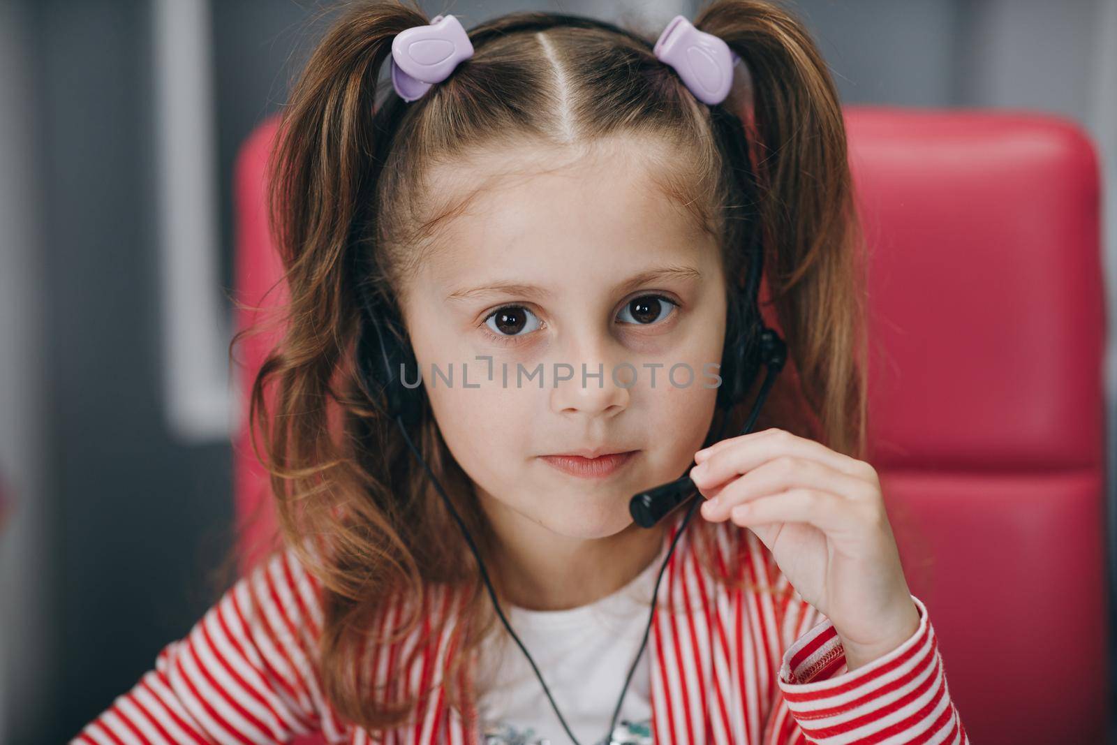 Cute happy little girl with headphones. Girl with headphones. Little cute child girl wearing headphones. Preschool girl or kid listening to music on gray background. Melody,sound and music concept