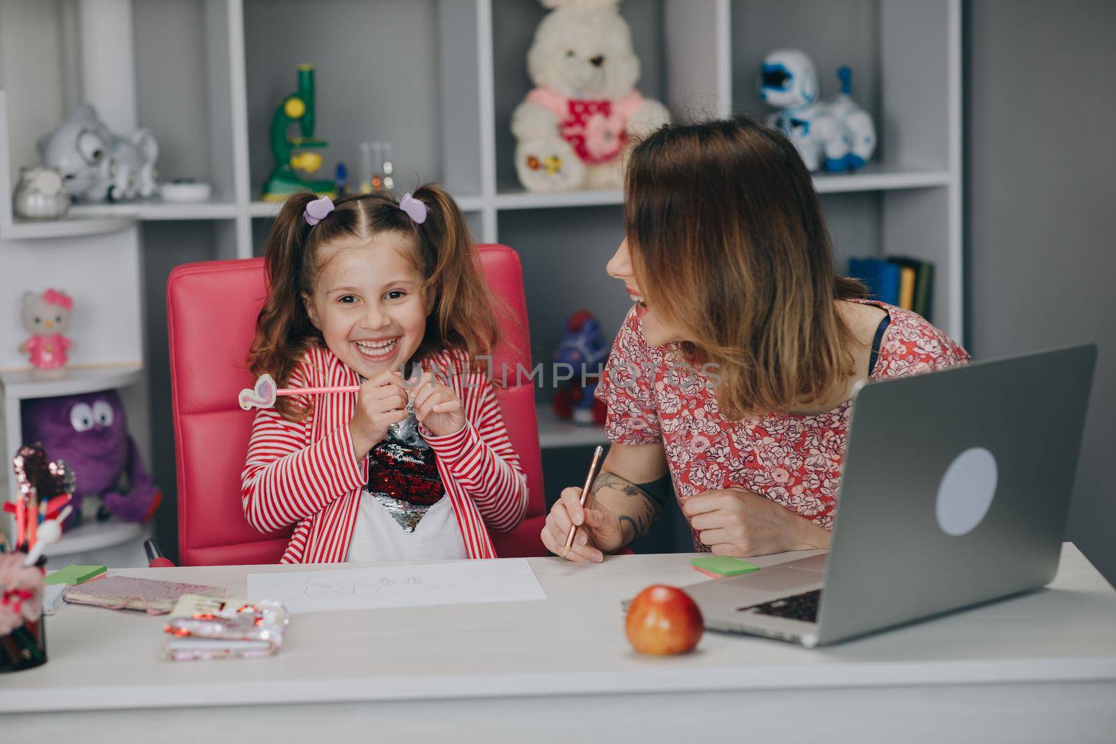 Distance learning online education. Schoolgirl with laptop notebook and doing school homework. Mom does homework with her daughter at home.