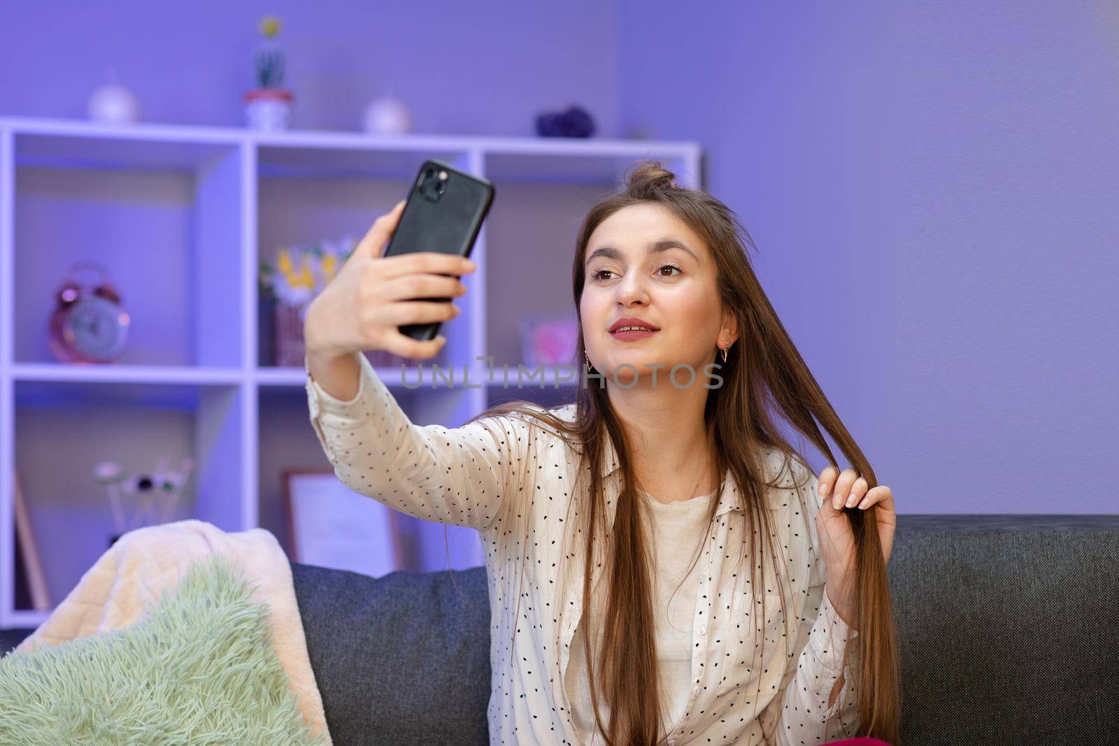 Happy young woman blogger influencer holding modern smart phone wave hand hello. Smiling vlogger girl looking at mobile make video call, shooting vlog taking selfie by uflypro