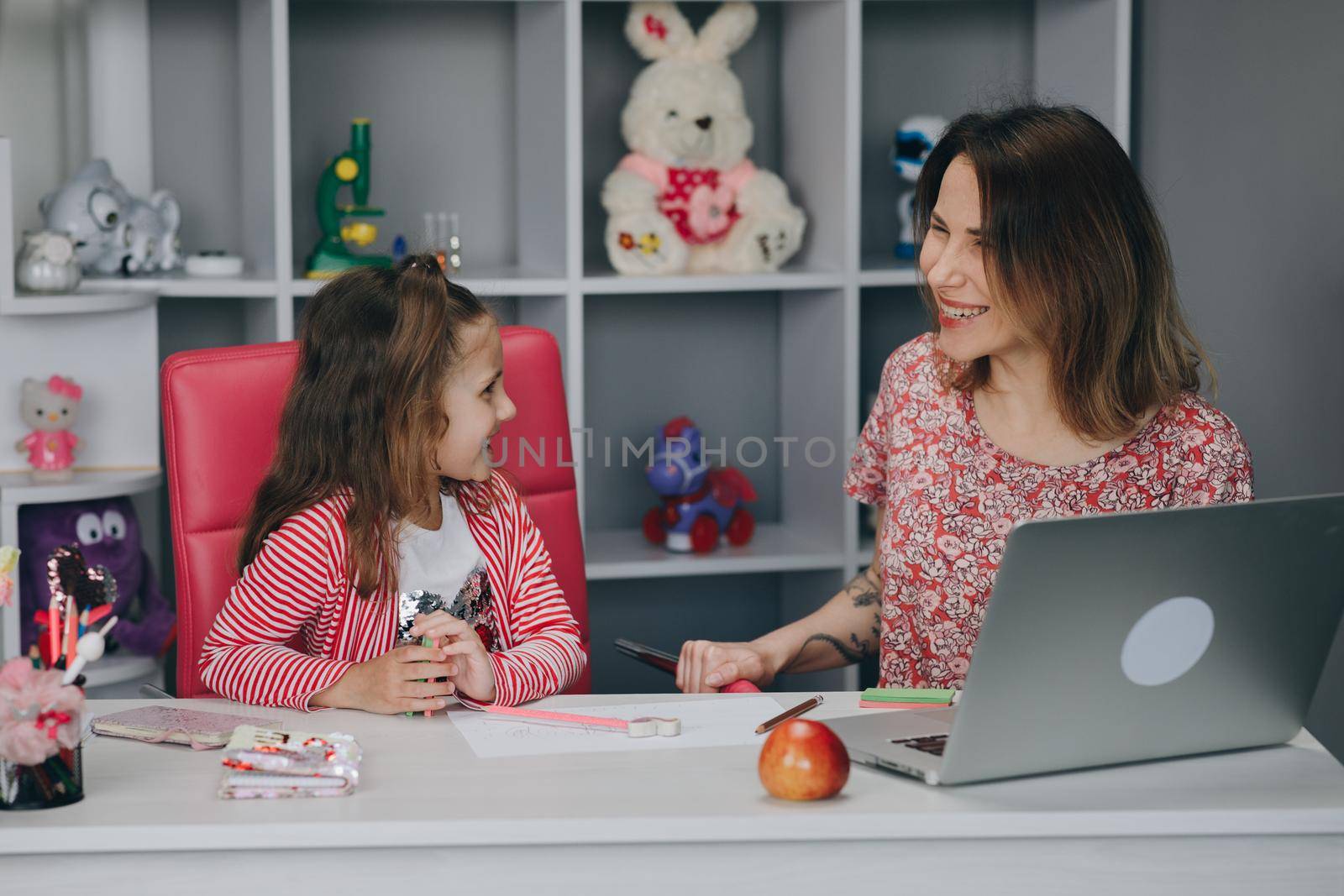 Mother and kid at home doing homework online. Distance learning online education. Mom does homework with her daughter at home by uflypro