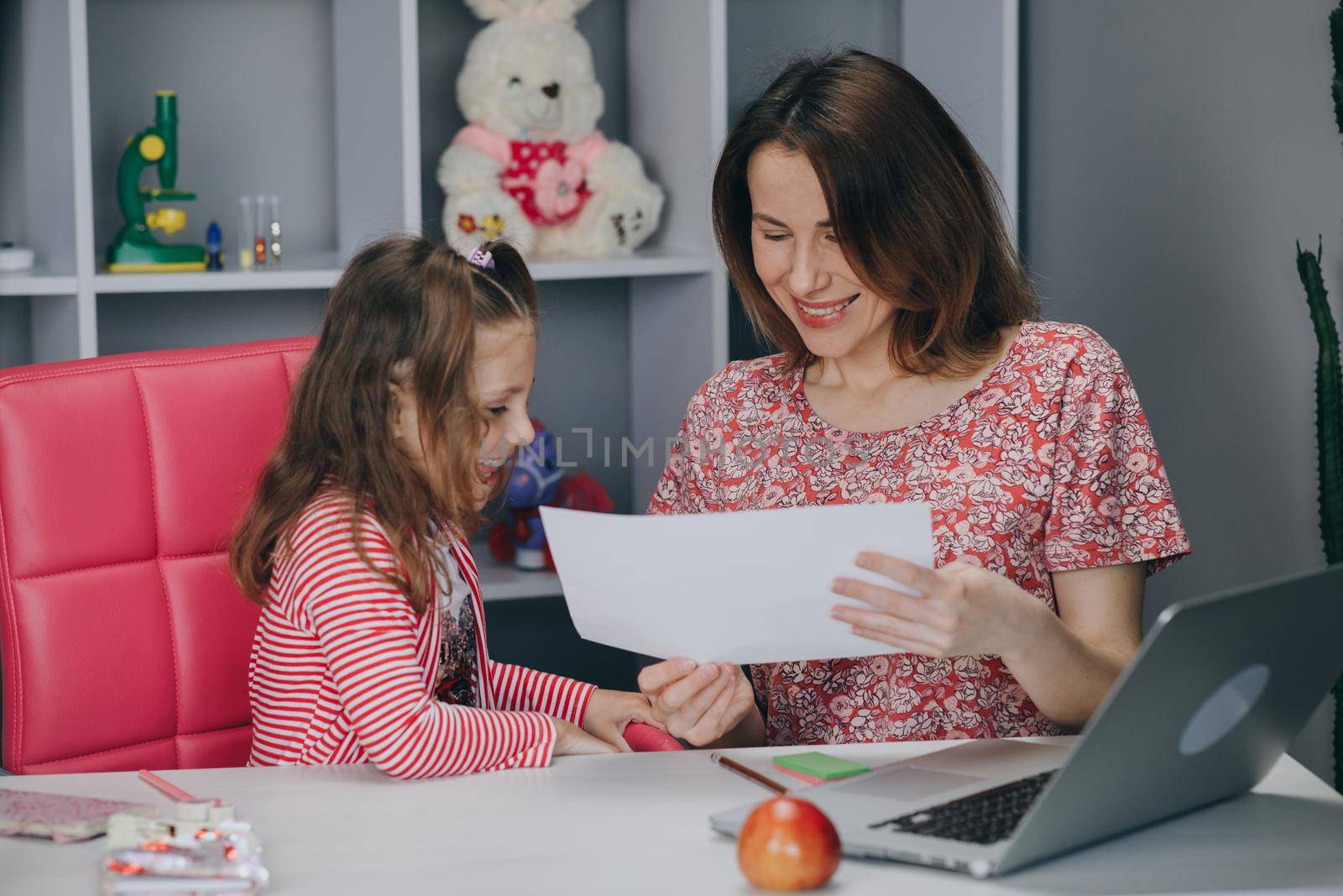 Distance learning online education. Schoolgirl with laptop notebook and doing school homework. Mom does homework with her daughter at home.