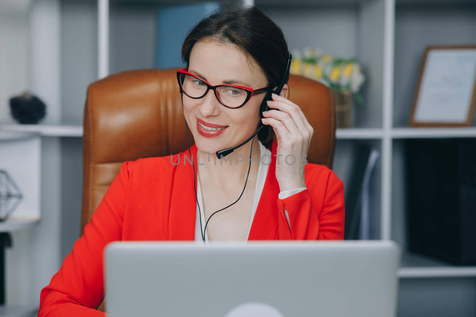 Happy young woman wear headset communicating by conference call speak looking at computer at home office. Video chat job interview or distance language course class with online teacher concept