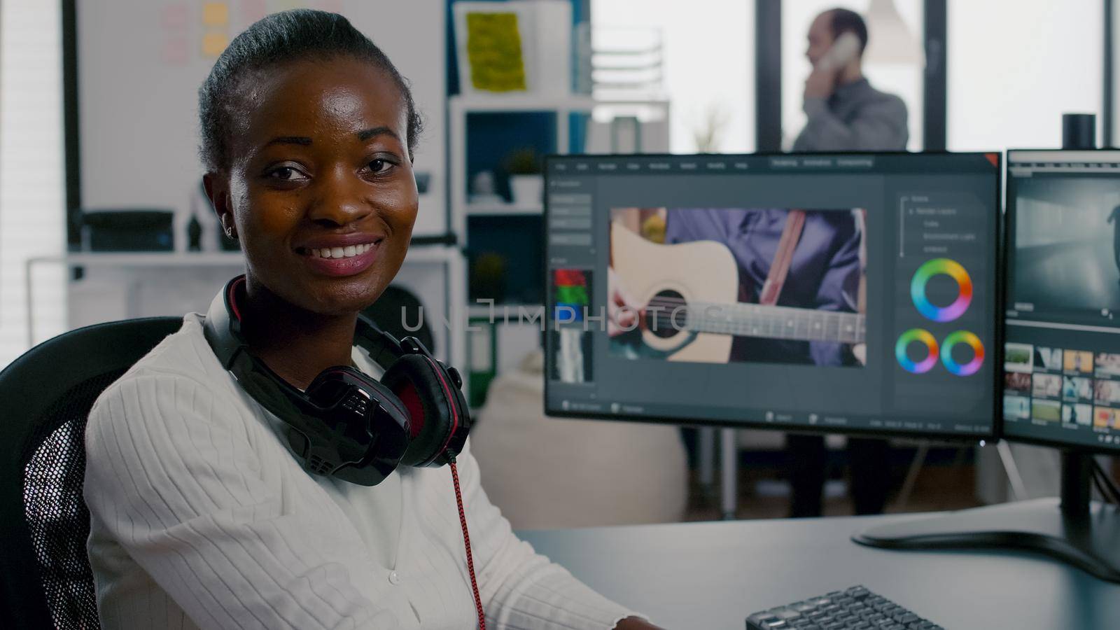 Close up of african video editor turning head at camera looking and smiling working in start up creative agency office. Black videographer editing video project using post production software