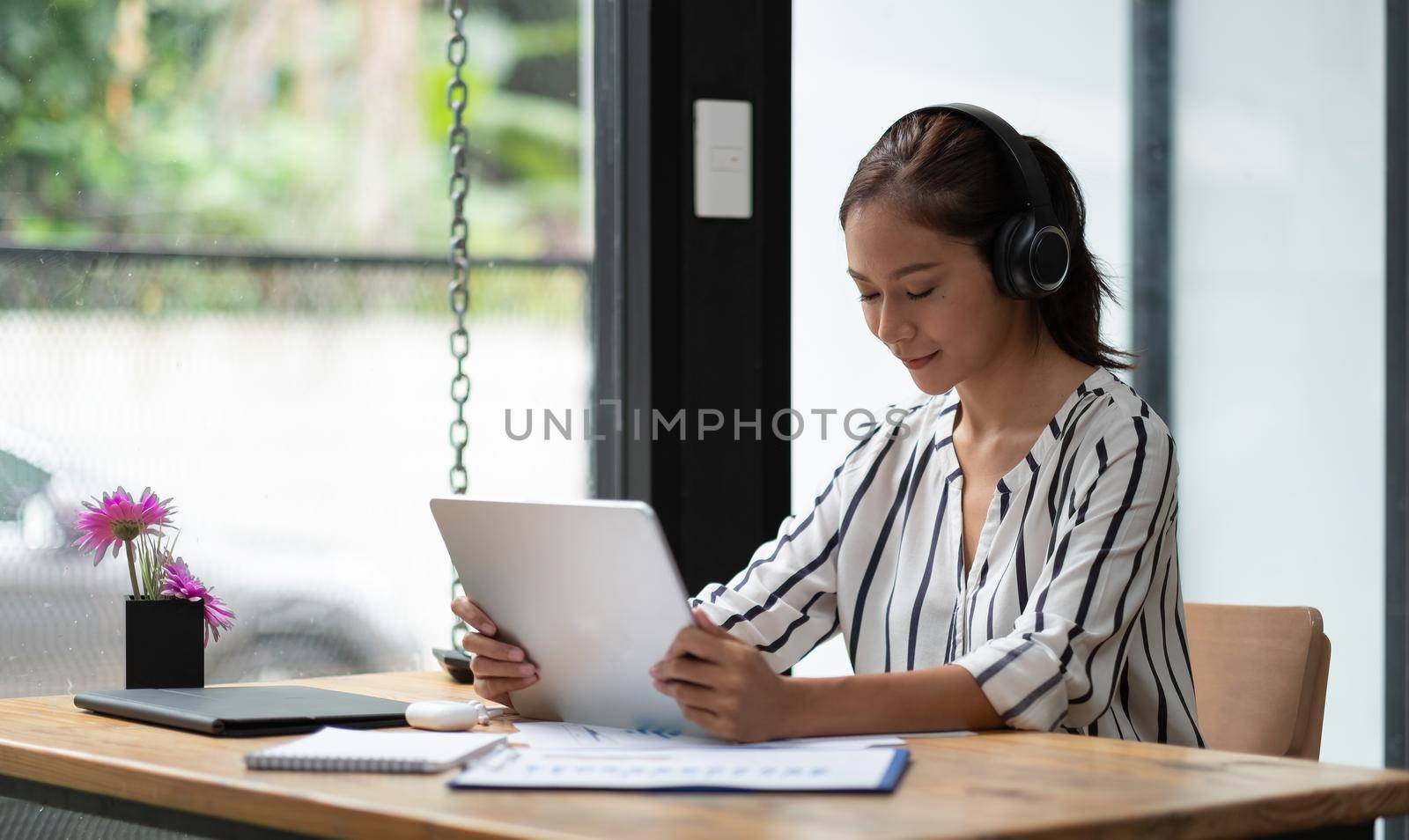 Relax time, Asian girl with headset listening music on line with a tablet sitting on working space by nateemee