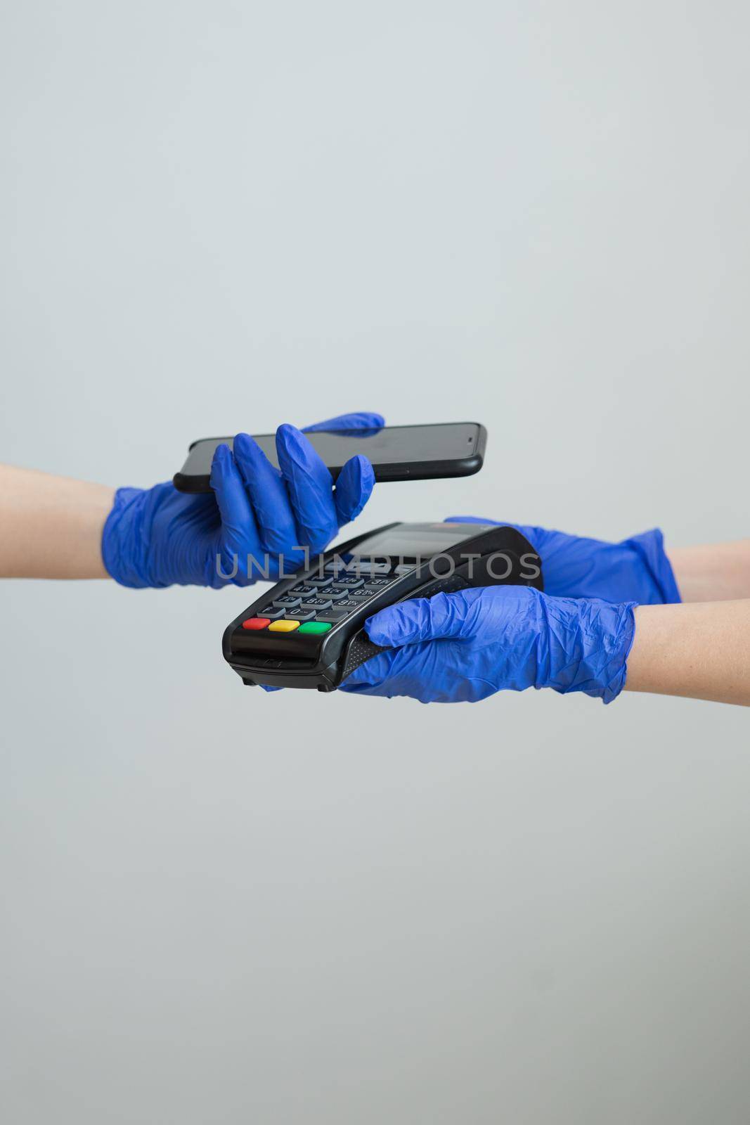 Nfc cellhone of female buyer with cashless wallet of e-money for pos card reader and checkout. Woman in gloves applies smartphone to terminal performing successful contactless payment.