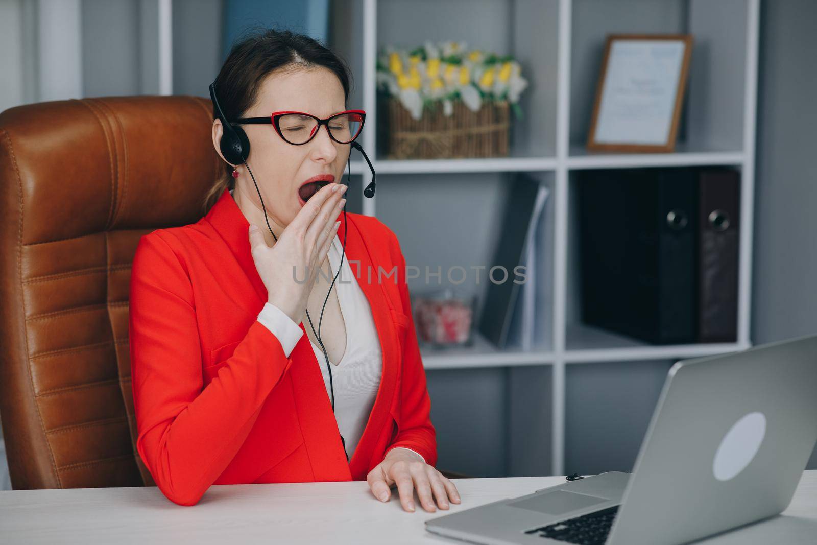 Call center operator is tired of talking to people asking stupid questions. Young customer service representative at work. Young female worker productively operating at call-centre