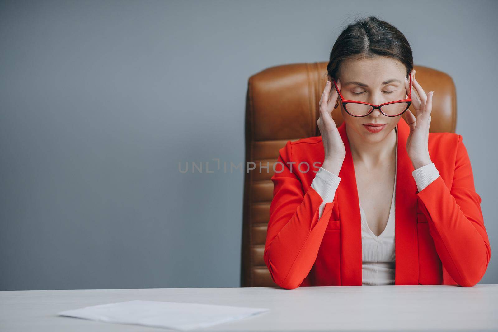 Feeling Tired and Stressed. Frustrated Young Woman Keeping Eyes Closed and Massaging Nose While Sitting at Her Working Place in Office by uflypro