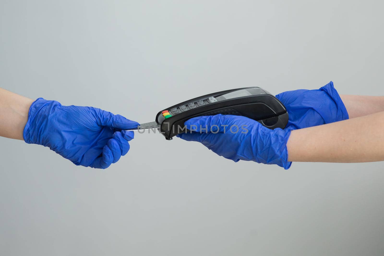 Female holding in hands wireless modern bank payment terminal to process acquire credit card payments black card isolated on grey background. Hands hygiene prevention of coronavirus outbreak.