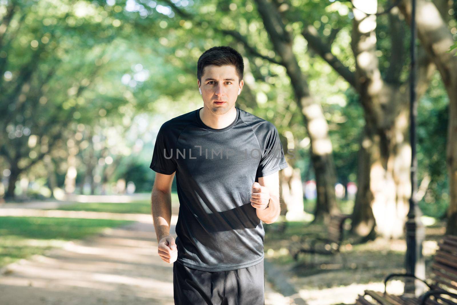 Young man in sportswear running in park in the morning. Active lifestyle. Health care and sports. Sporty man running.