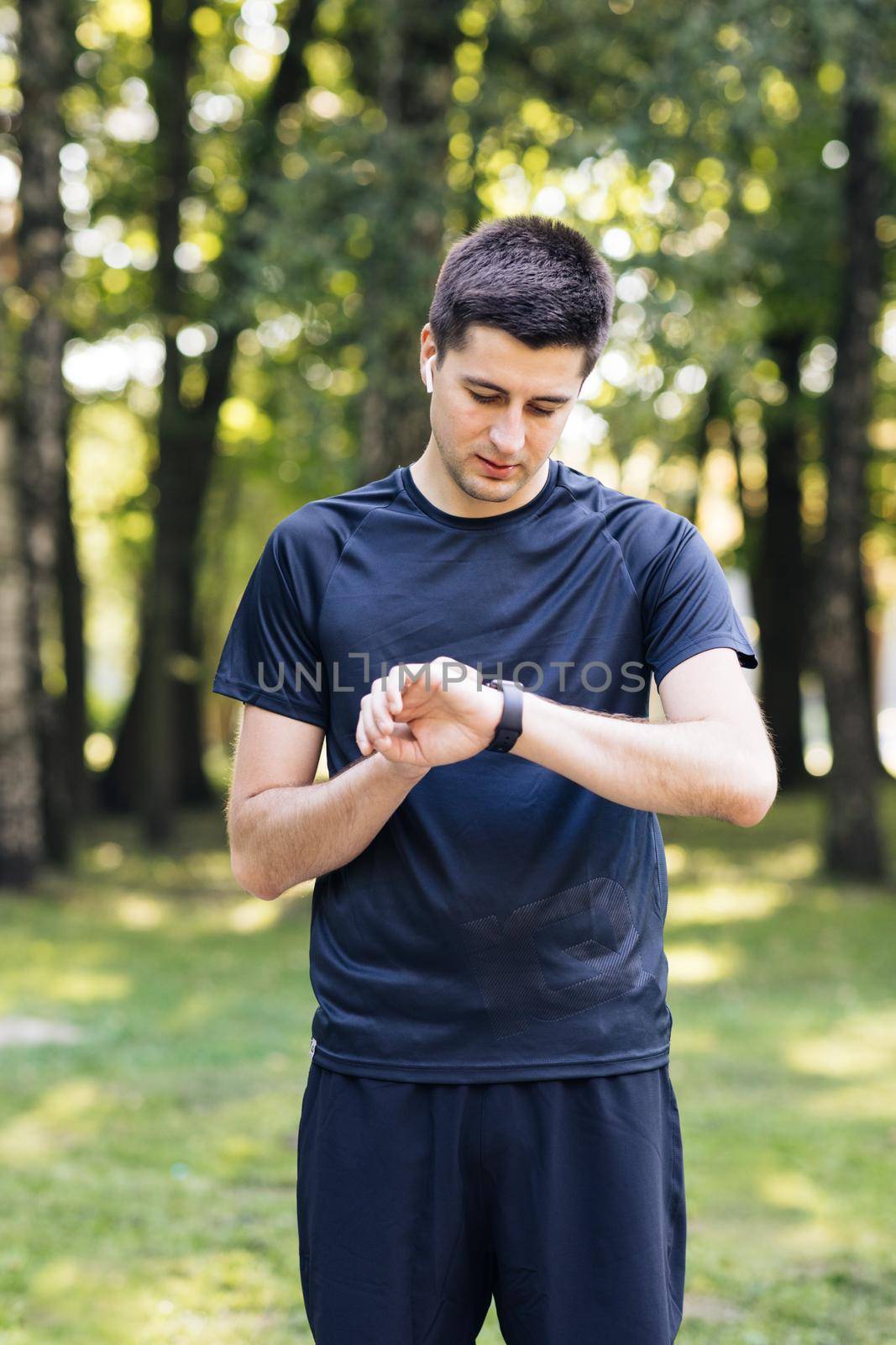 Sport man looking smart watch. Man runner using smart watch. Handsome guy tracking result after workout. Portrait of fitness man checking result.