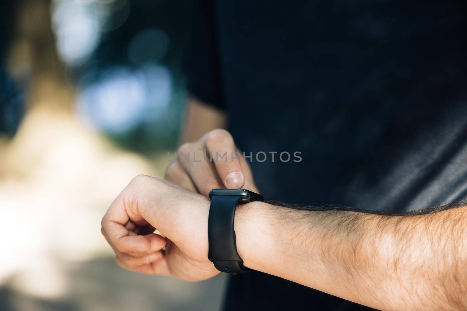 Close up view of male hand with modern smart watch gadget outside Black touchscreen. Checking notification online. Measuring distance, heart rate. Healthcare.