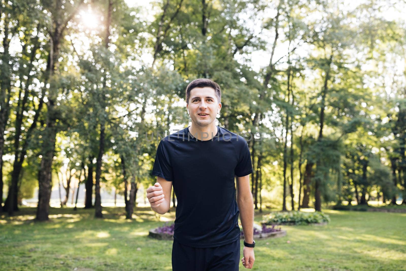 Adult man in sportswear jogging on the park in early morning. Sports people. Sportsman. Running activity. Healthy lifestyle by uflypro