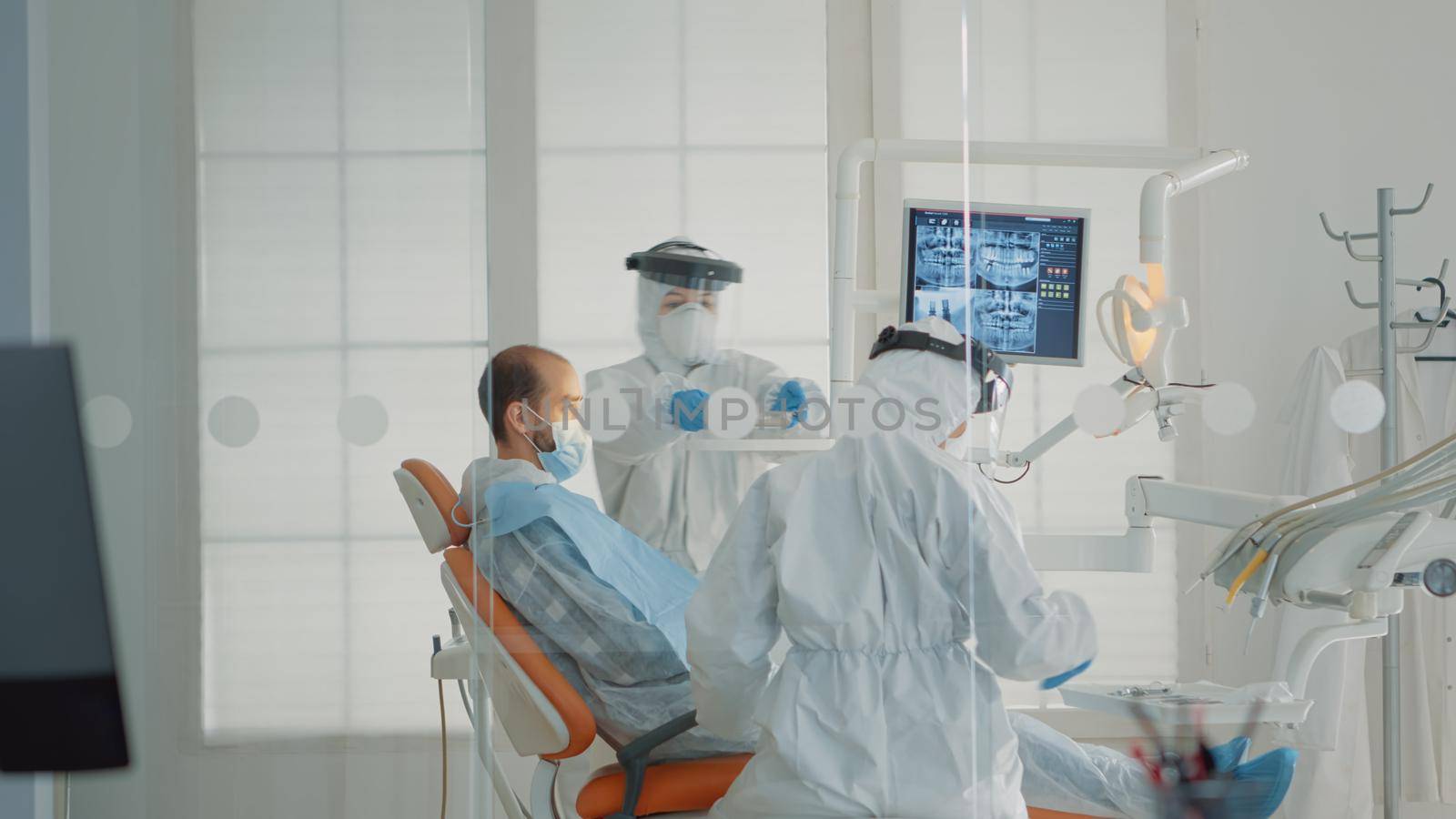 Team of dentists and patient sitting in dental cabinet by DCStudio