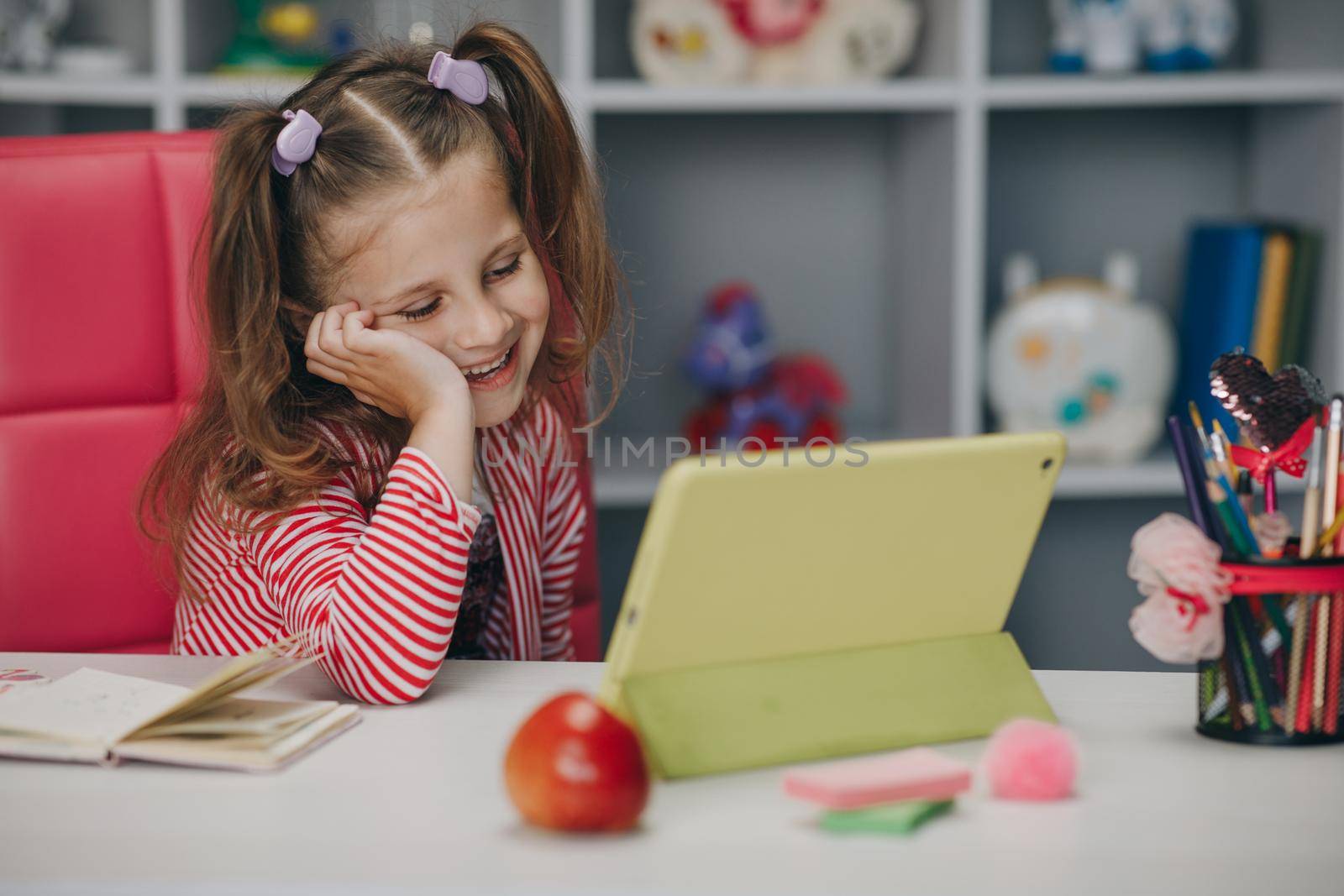 Curious cute preschool kid girl using digital tablet technology device. Small child hold pad computer surfing internet play game at home. Children tech addiction concept