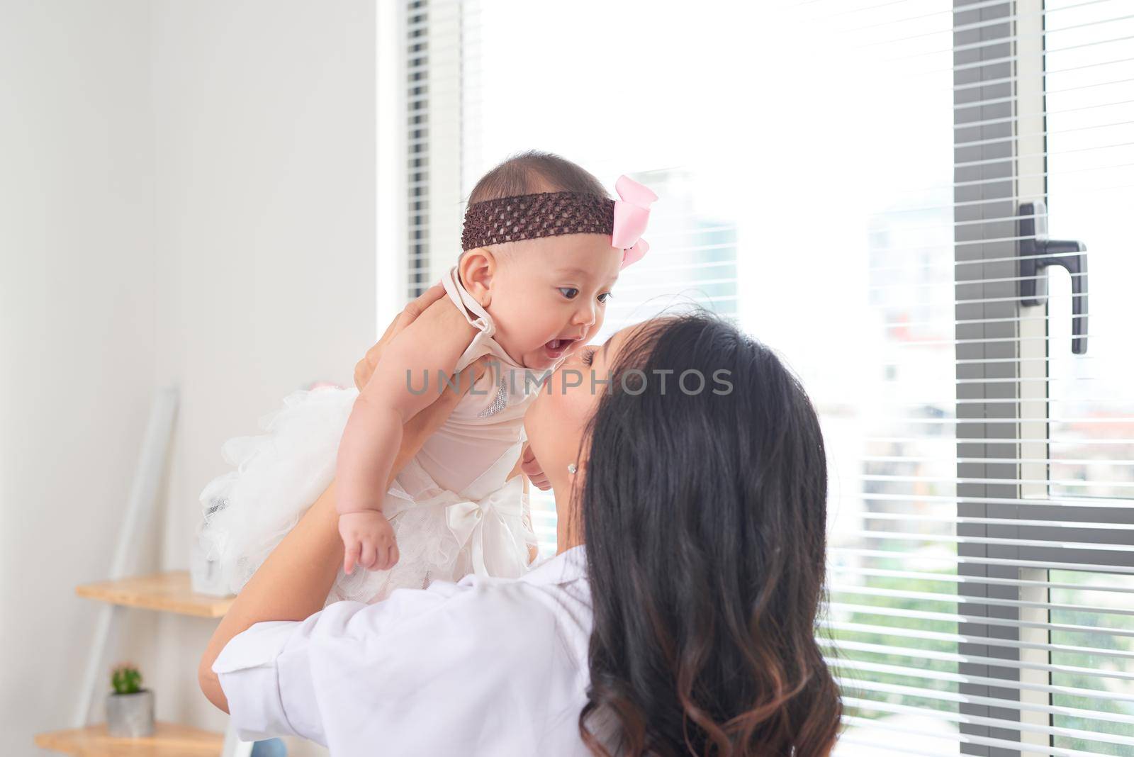 Mom kisses her little daughter  on a light background.