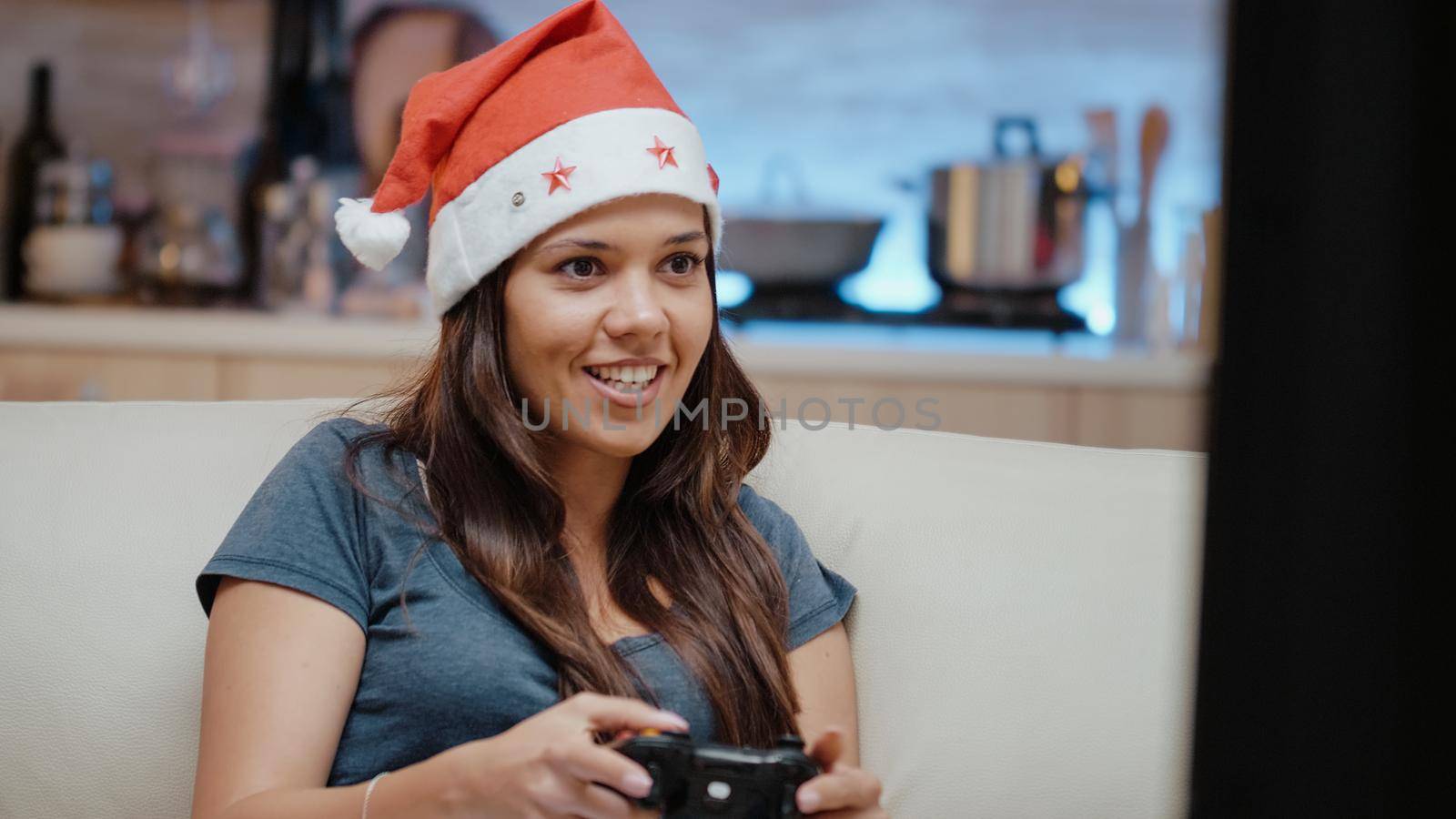 Person with santa hat winning video games with joystick on console at home. Festive woman playing games online feeling cheerful using controller and television to celebrate christmas eve