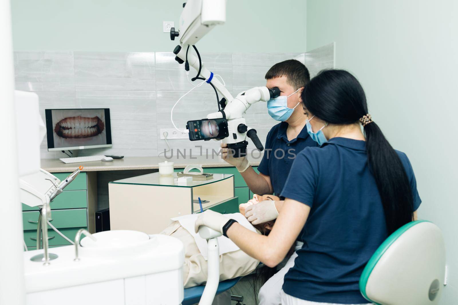 Medical Stomatology Concept. Doctor making teeth examination research survey using microscope in dentistry. Dentist is treating patient in modern dental office by uflypro