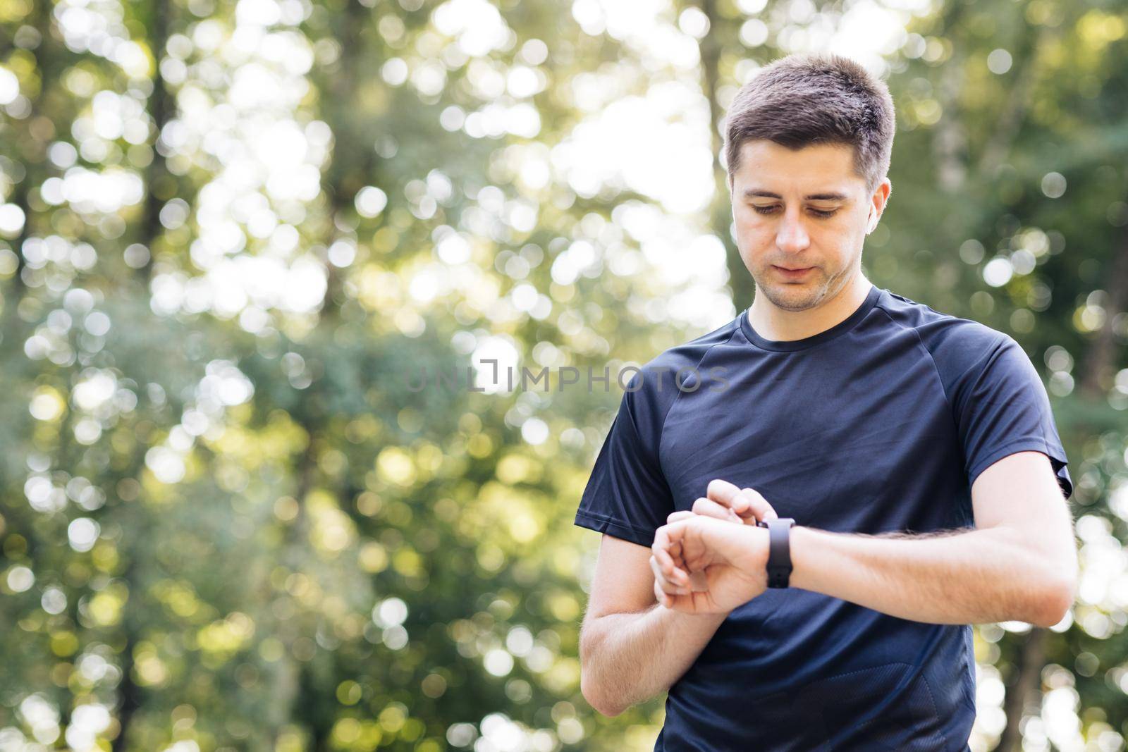 Sport man looking smart watch. Man runner using smart watch. Handsome guy tracking result after workout. Portrait of fitness man checking result