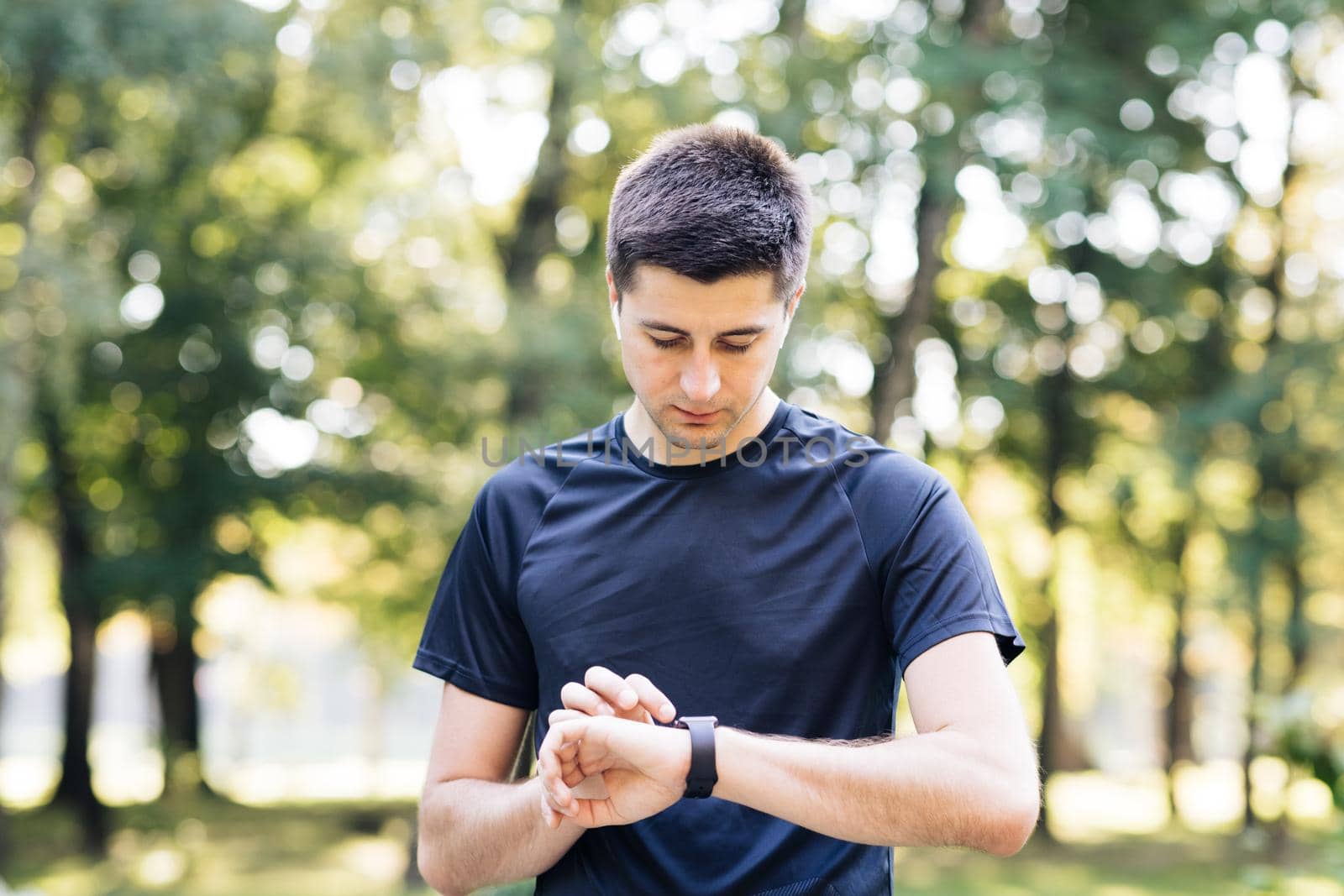 Caucasian man in sports uniform using smartwatch to measure speed, distance, heartbeet caring about physical body health. Futuristic technology. Mock up by uflypro