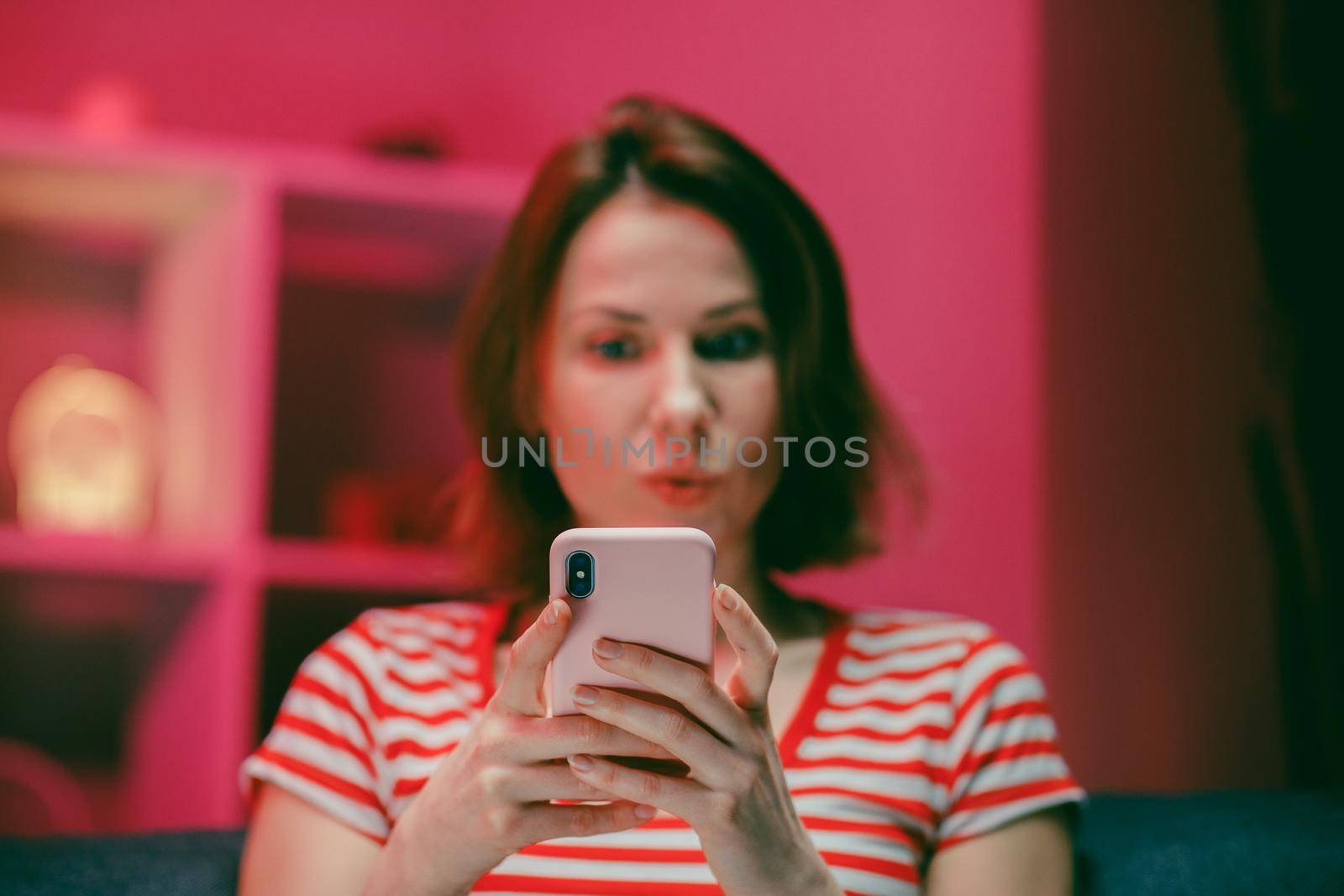 Woman Holding Smart Phone Looking at Cellphone Screen Laughing Enjoying Using Mobile Apps for Shopping. Having Fun Playing Games Chatting in Social Media Sit on Couch at Home by uflypro