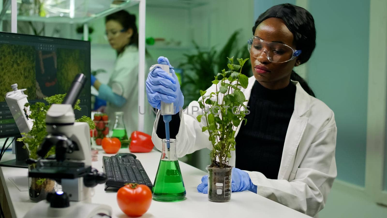 African botanist researcher taking genetic solution from test tube by DCStudio