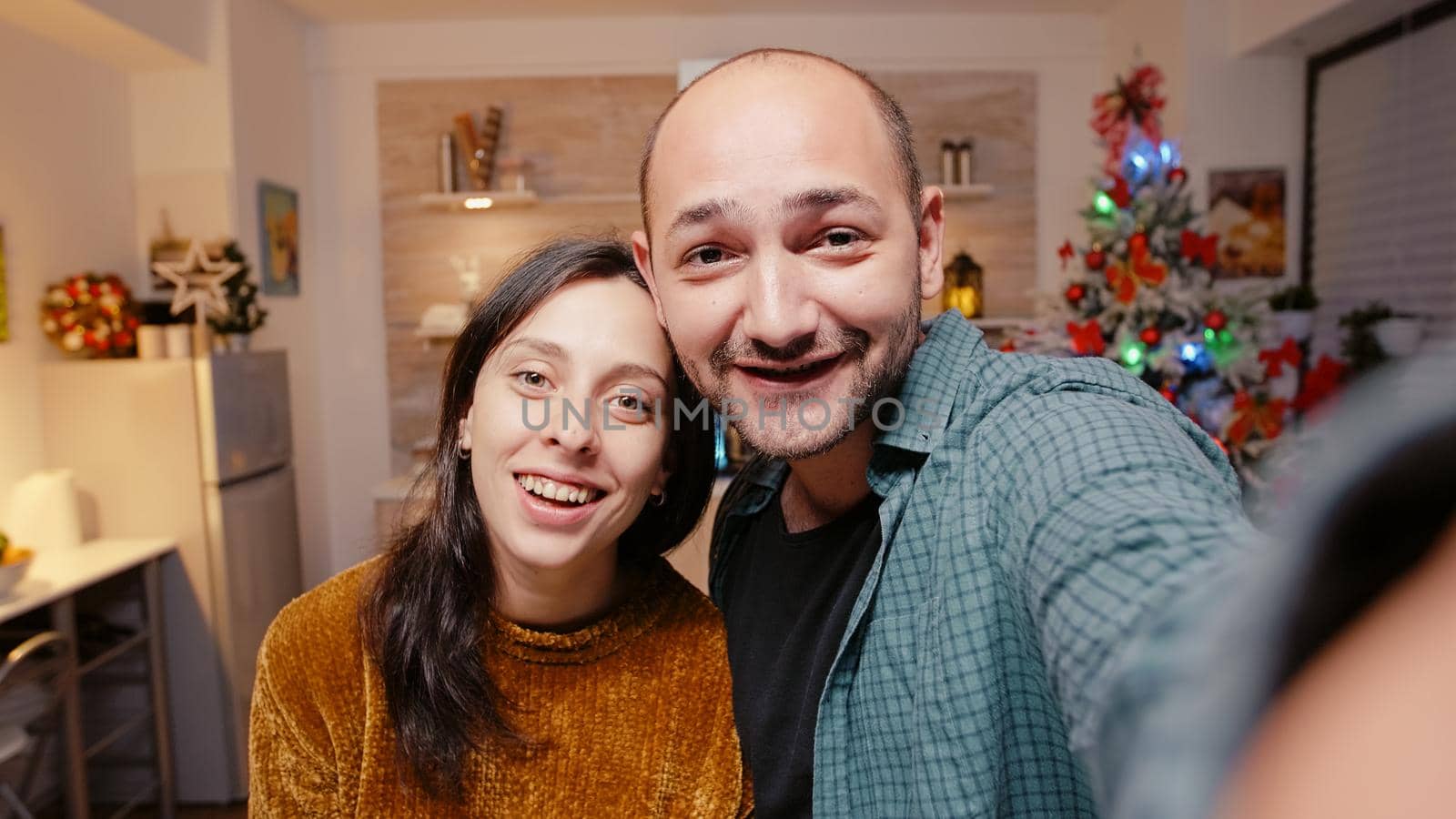 POV of cheerful couple using video call conference to talk to family on internet. Festive man and woman celebrating christmas holiday with online remote communication. People enjoying festivity