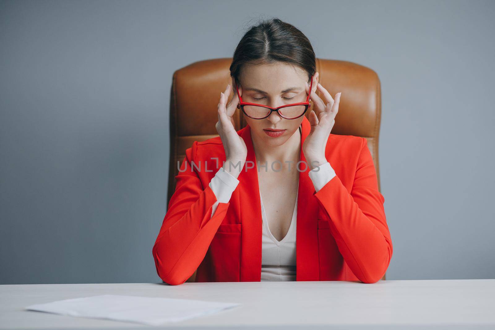 Frustrated young woman keeping eyes closed while sitting at her working place in office. Businesswoman is tired and feels stressed out. Feeling tired and stressed.