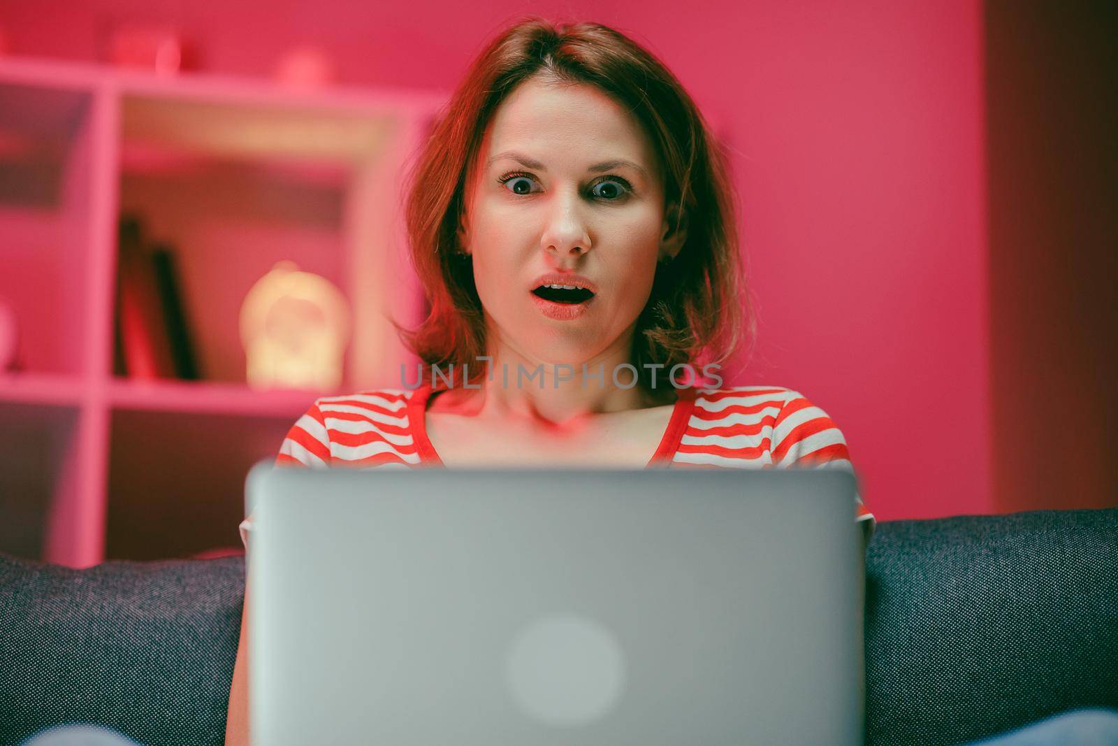 Surprised woman face looking at laptop screen. Close up of excited woman watch online news at computer. Portrait of happy girl shopping website at laptop. by uflypro