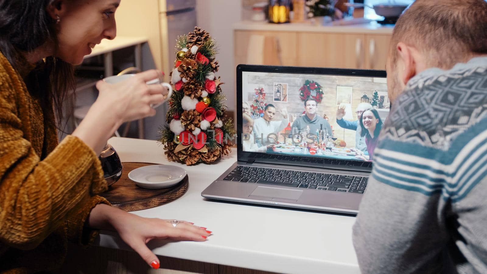Festive couple talking to family on video call at christmas dinner by DCStudio