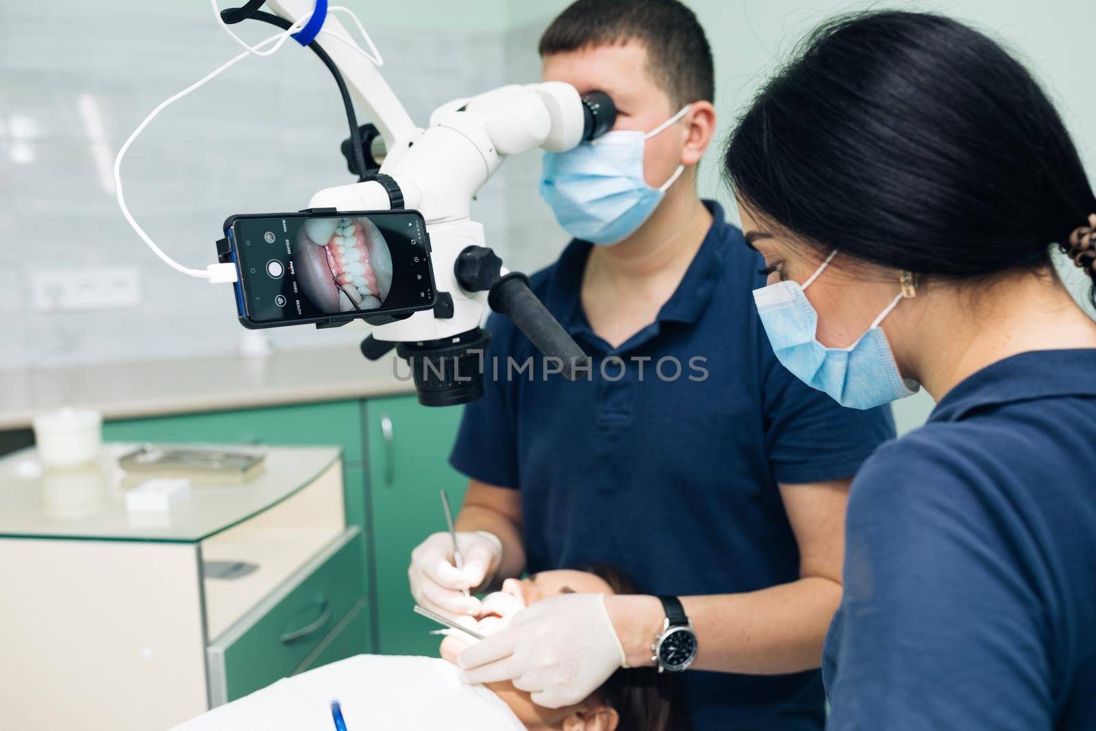 Modern dental clinic with microscope tool for treatment patients. Doctor hand in protective glove putting medical microscope. Man dentist uses microscope. Medical equipment, dental clinic.