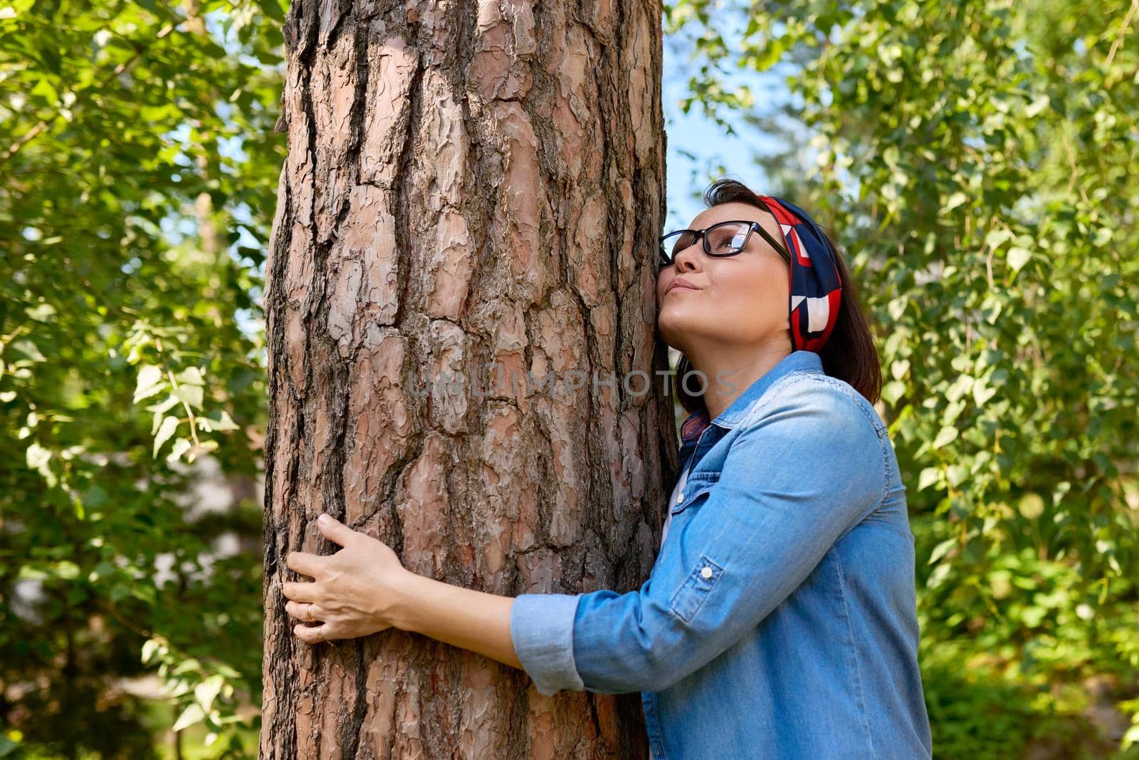Middle aged woman hugging a tree, energy of nature. Relaxation, mental health, rest, freedom, mature people concept