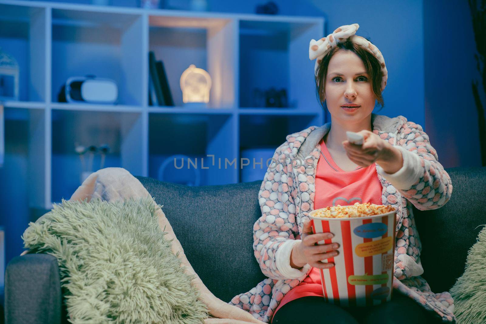 Pretty woman watching something funny on tv at home. Eating popcorn by uflypro