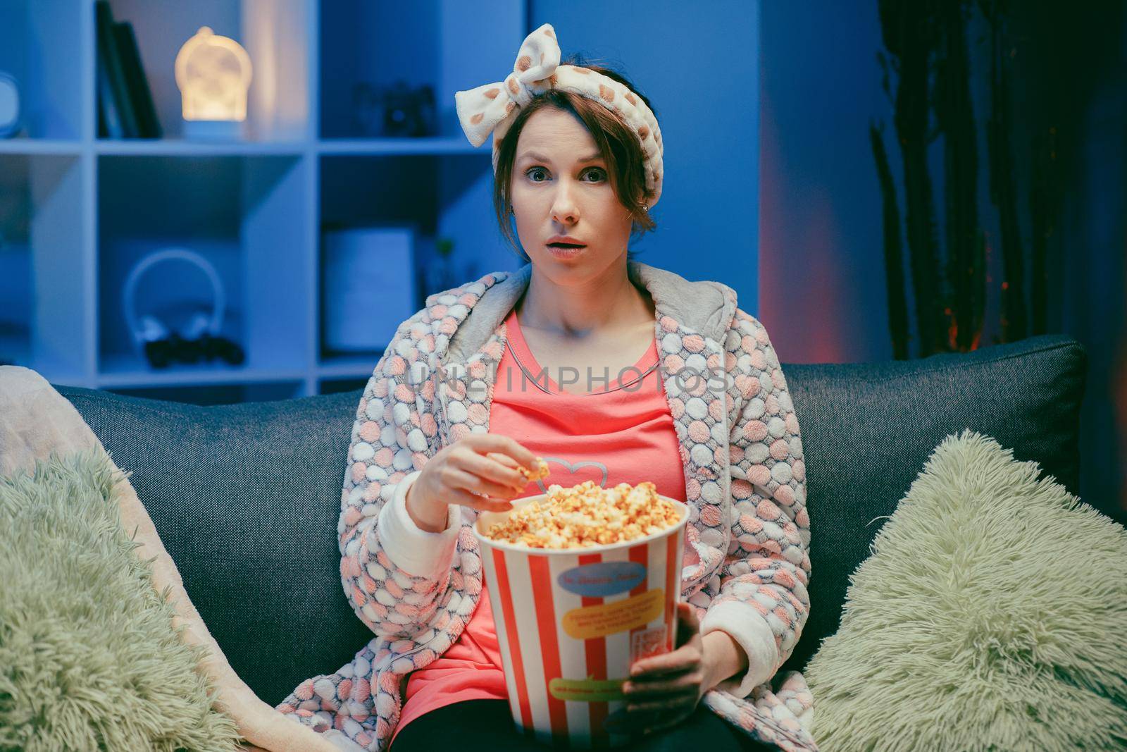 Woman watching TV laughing and eating popcorn having fun at home alone enjoying modern television. Youth lifestyle and cheerful people concept by uflypro