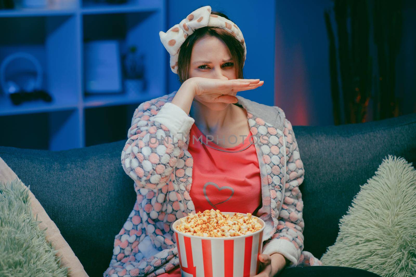 Woman cry while watching a very moving movie with popcorn at night. by uflypro