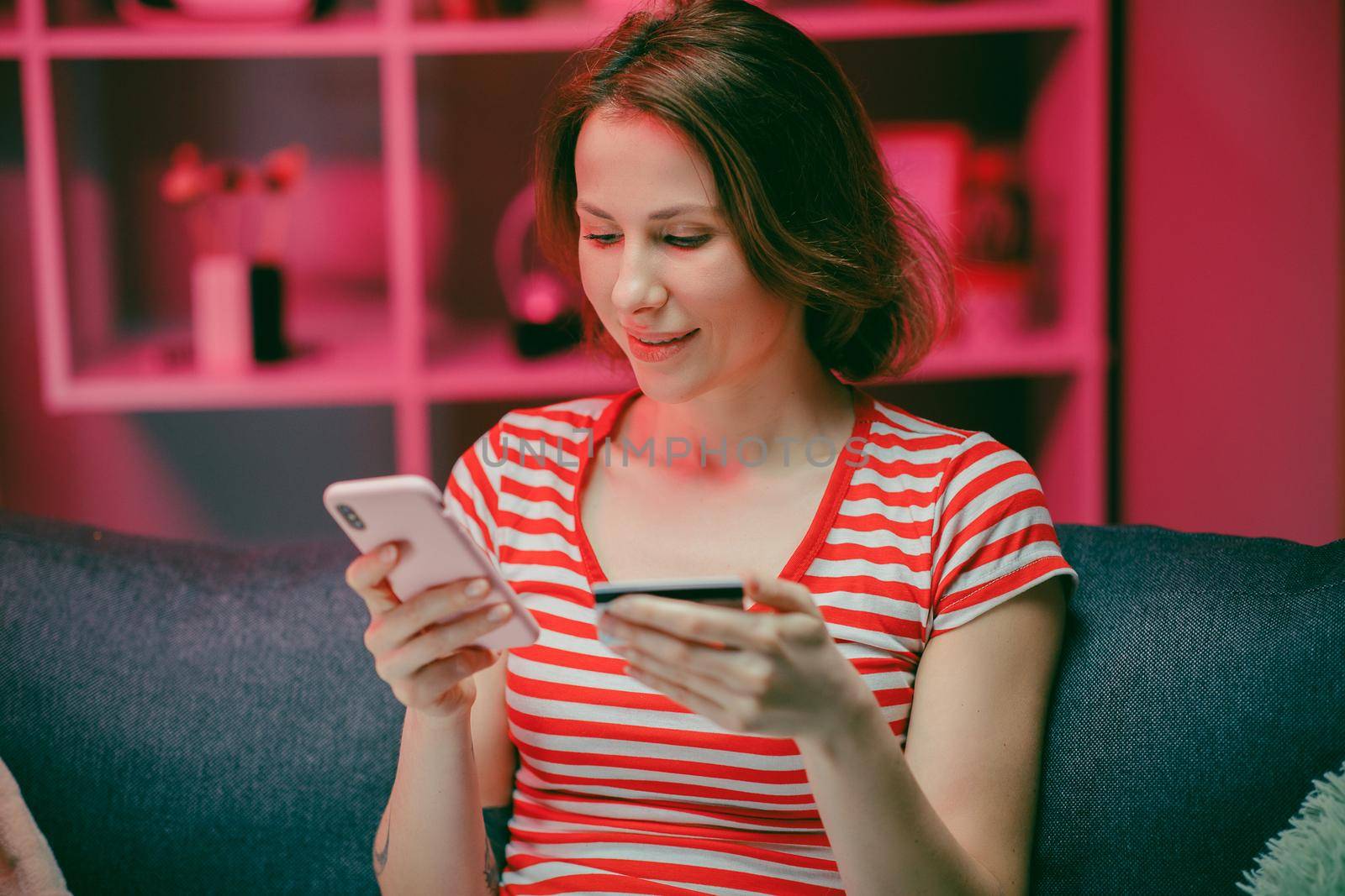 Beautiful woman are buying online with a credit card and smile while sitting on the sofa at home. Woman are using smart phone and doing online transactions, Past the internet