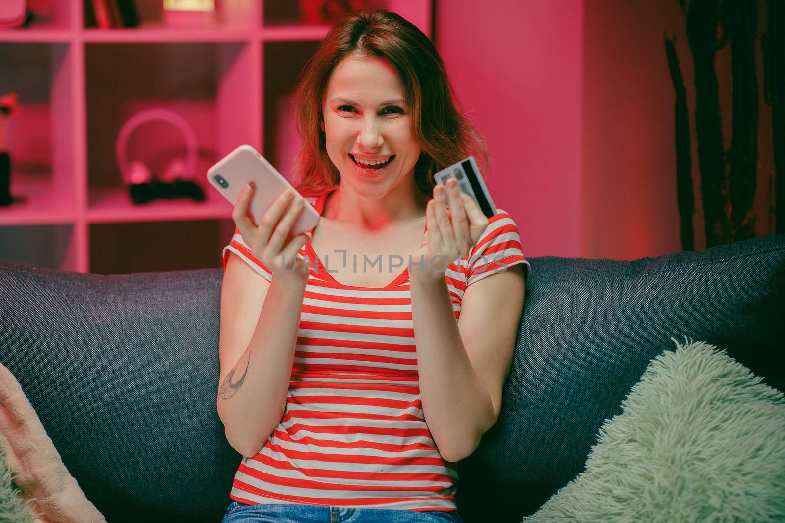 young woman are buying online with a credit card while sitting on the sofa in the living room. Women are using smartphone and doing online transactions.