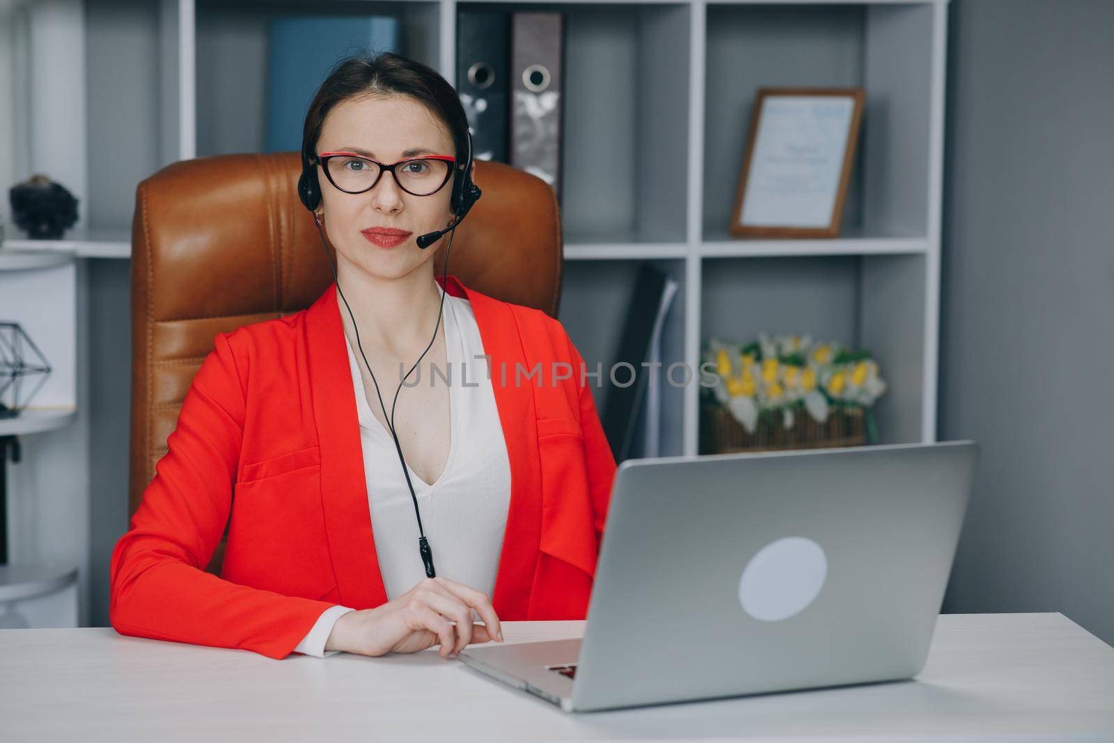 Happy woman wear headset communicating by conference call speak looking at camera at home office. Video chat job interview or distance language course class with online teacher concept.
