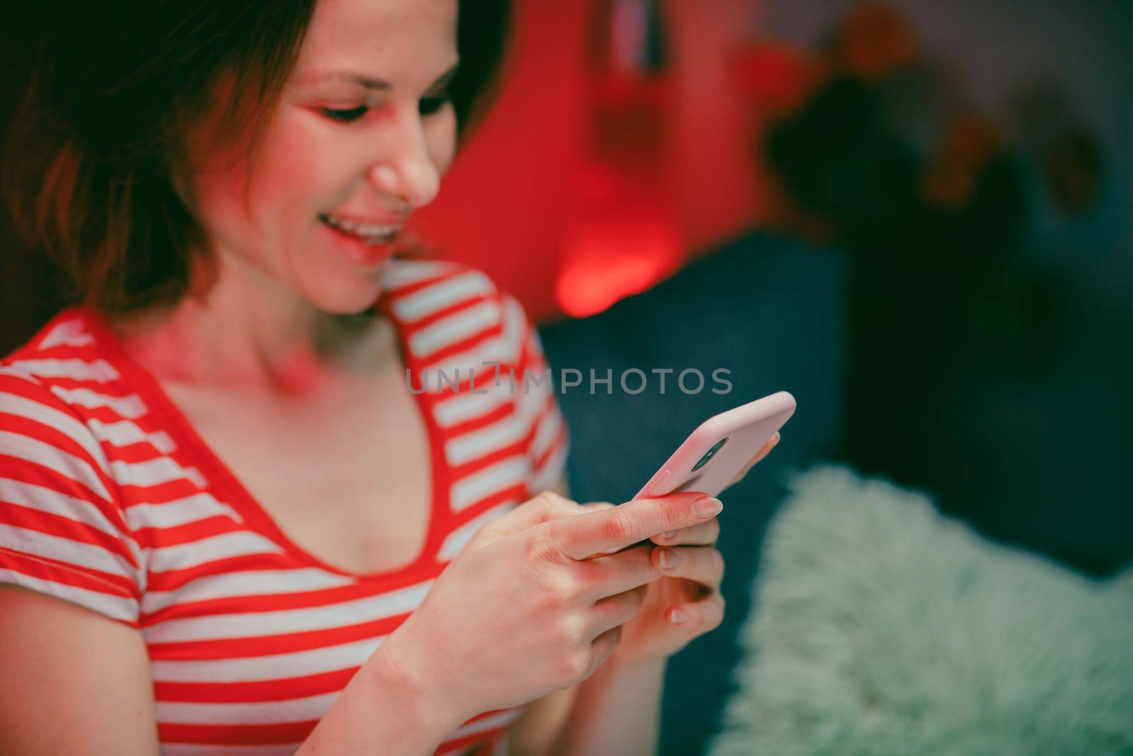Woman Holding Smart Phone Looking at Cellphone Screen Laughing Enjoying Using Mobile Apps for Shopping. Having Fun Playing Games Chatting in Social Media Sit on Couch at Home by uflypro