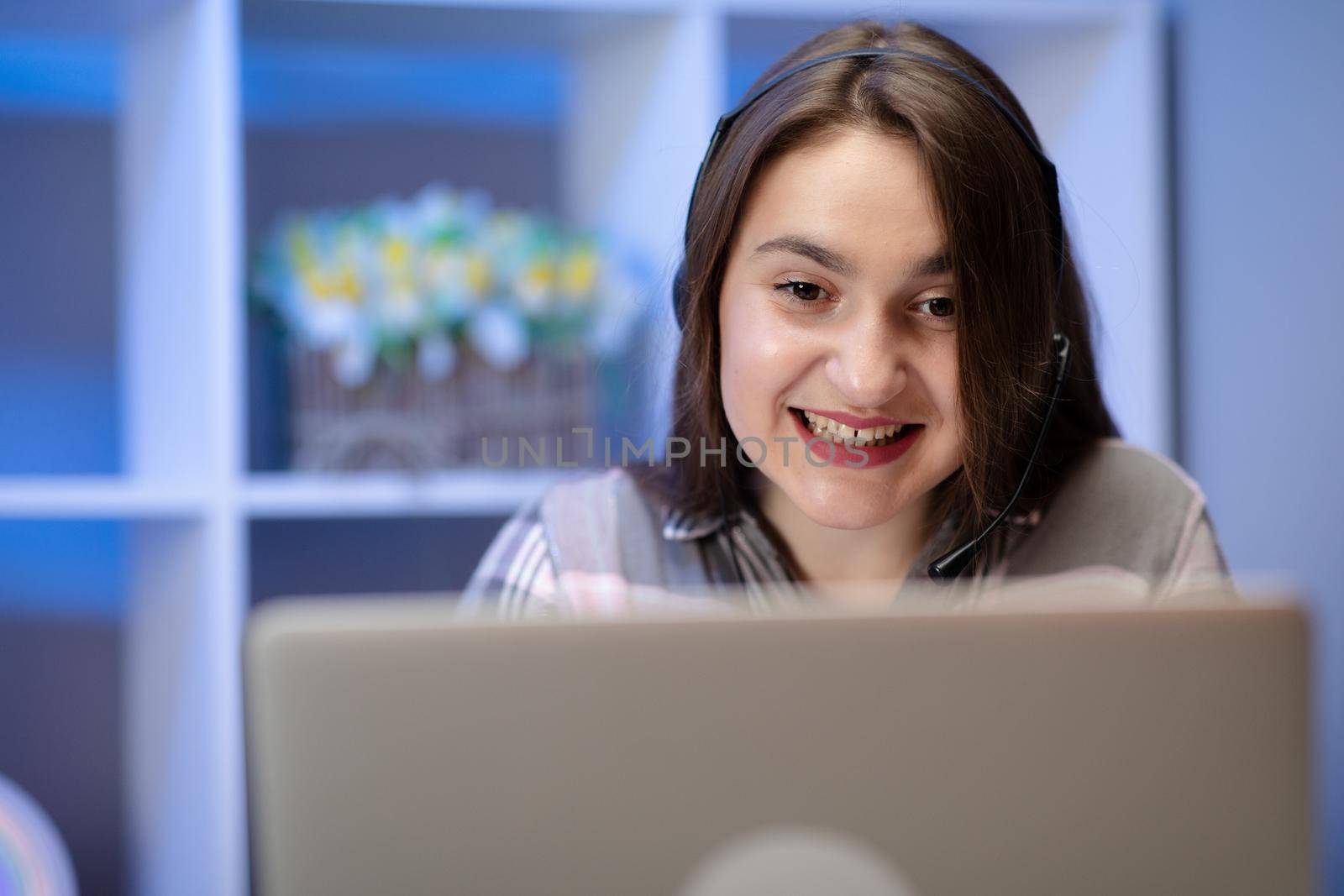 Teen girl doing her homework online and listening to headphones. Young College Girl Uses Her Laptop. by uflypro
